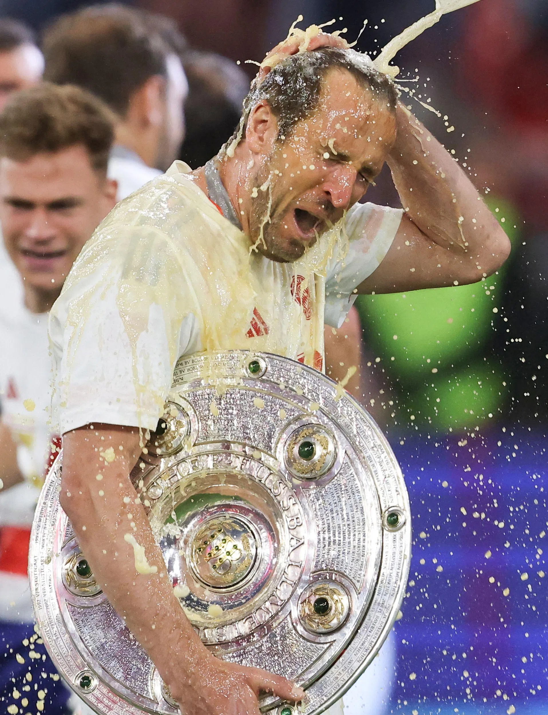抱着自己首座大赛冠军奖杯的凯恩被队友泼洒啤酒庆祝。此前，凯恩曾七次在大赛屈居亚军，这次他也如愿打破了“无冠魔咒”。（法新社）
