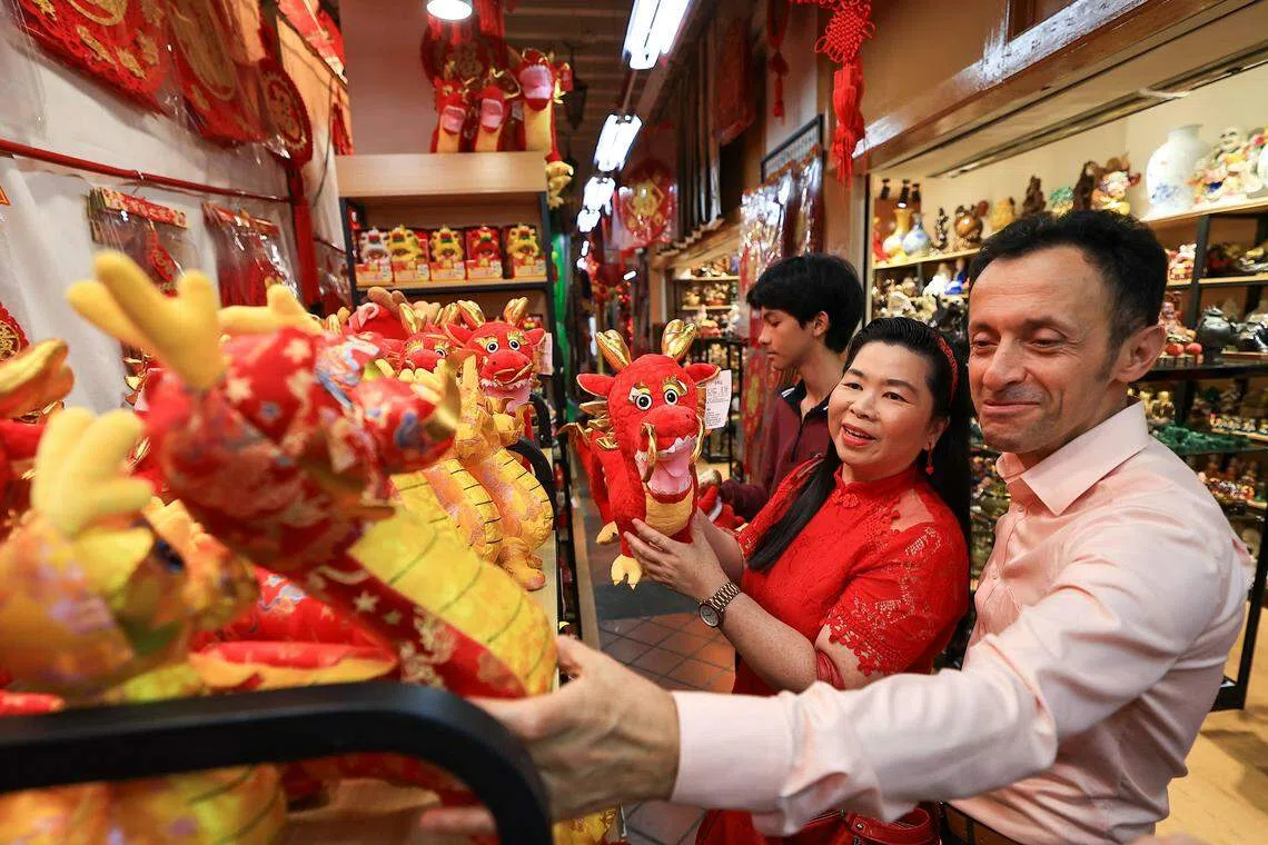 陈慧彬带着丈夫奥格和儿子劢迩文一起逛牛车水年货市场，一家人开心地选购龙年饰品。（吴先邦摄）