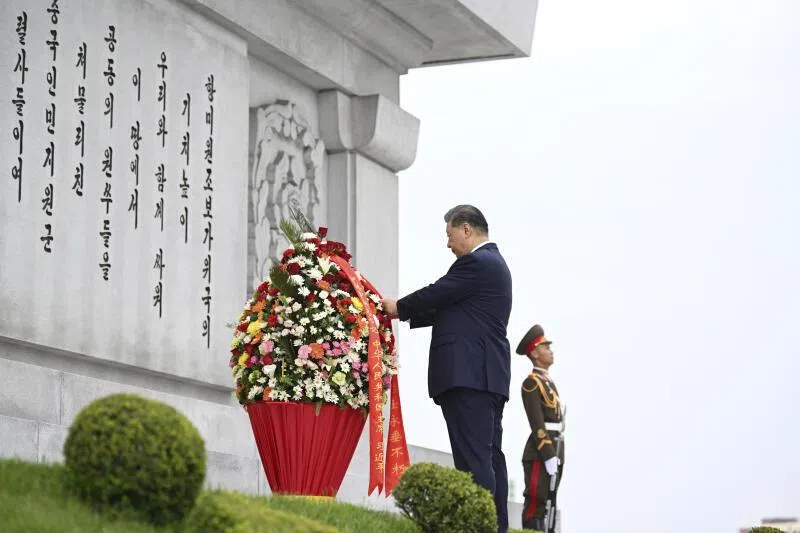 中国国家主席习近平和夫人彭丽媛星期二（6月9日）上午参谒中朝友谊塔。朝鲜最高领导人金正恩和夫人李雪主陪同。图为习近平整理花篮缎带。（新华社）