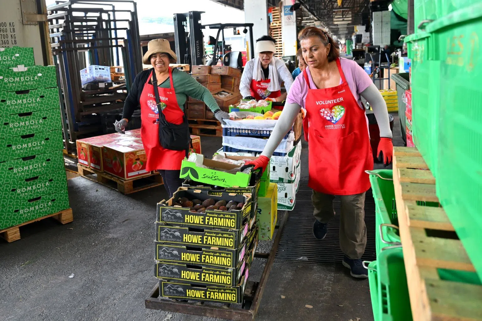 Volunteers from Fridge Restock Community SG, wearing their signature red aprons, push a trolley of fruit during a food rescue operation.