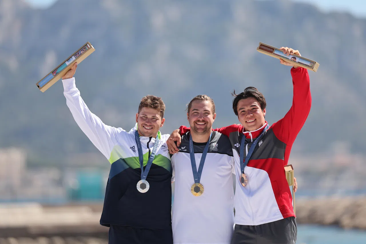 奥地利选手彭塔斯（中）连胜三场决赛，率先累积三场胜利，反超原本领先的斯洛文尼亚好手沃迪塞克（左），成为奥运会史上首名男子水翼风筝板冠军。沃迪塞克和墨士廉分别获得银牌和铜牌。（谢智扬摄）