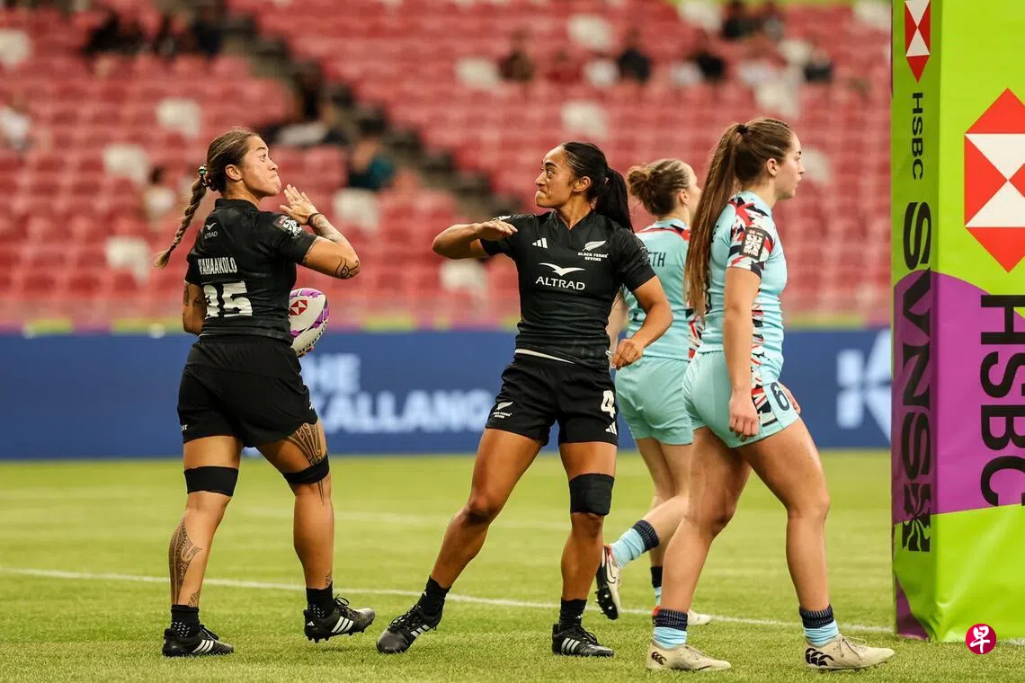 新西兰女队（黑衣）在团队揭幕战以64比0狂胜英国队（蓝衣），强势开启新加坡站三连冠征程。 （世界橄榄球联合会提供）