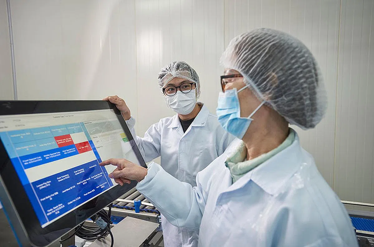 厂房数码化，年轻和年长员工皆受益。生产线主任邱世杰（左一）可以准确和轻松地查看存货，而年长员工也能减少体力透支，胜任愉快。（图/新报业集团） 