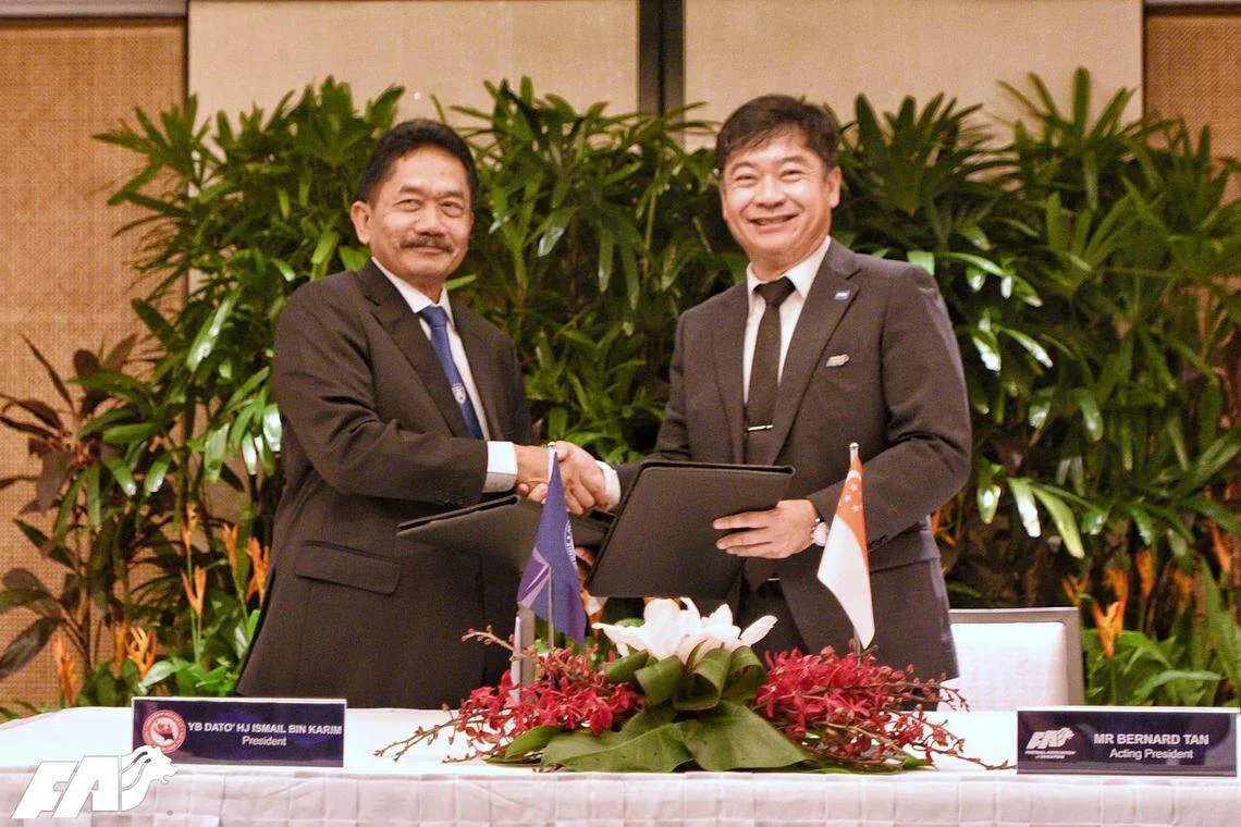 新加坡足总代理会长陈国强（右）和柔佛足总会长哈芝依斯迈，在签署谅解备忘录后握手及合照。（取自新加坡足球总会官网）