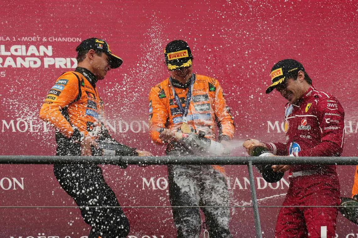 迈凯伦的诺里斯（左）和皮亚斯特里（中），以及法拉利车手勒克莱尔（右）在领奖台上互相喷洒香槟庆祝。（法新社）