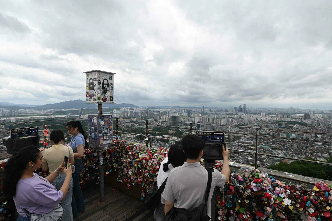 雨过天晴，游客在首尔市中心的地标性建筑南山塔欣赏城市美景。（法新社）