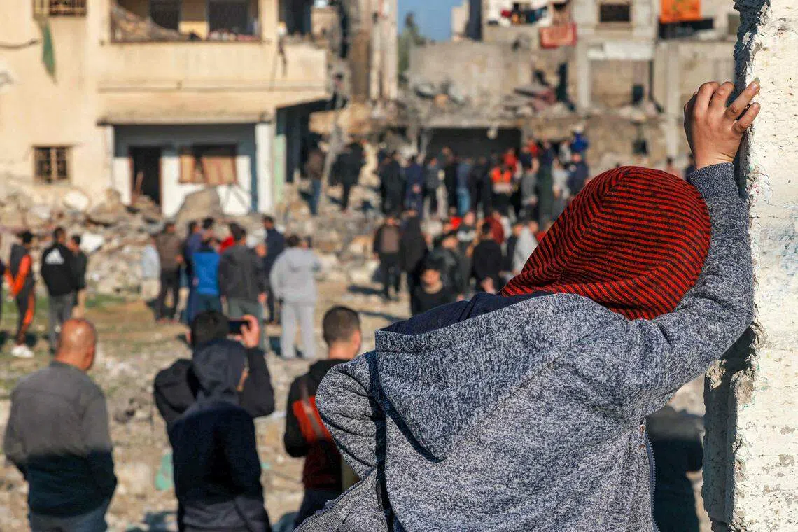 12月19日，在加沙南部靠近埃及边界的拉法市，人们聚集在被以军轰炸后遭摧毁的建筑物周围，检查事后情况。（法新社）