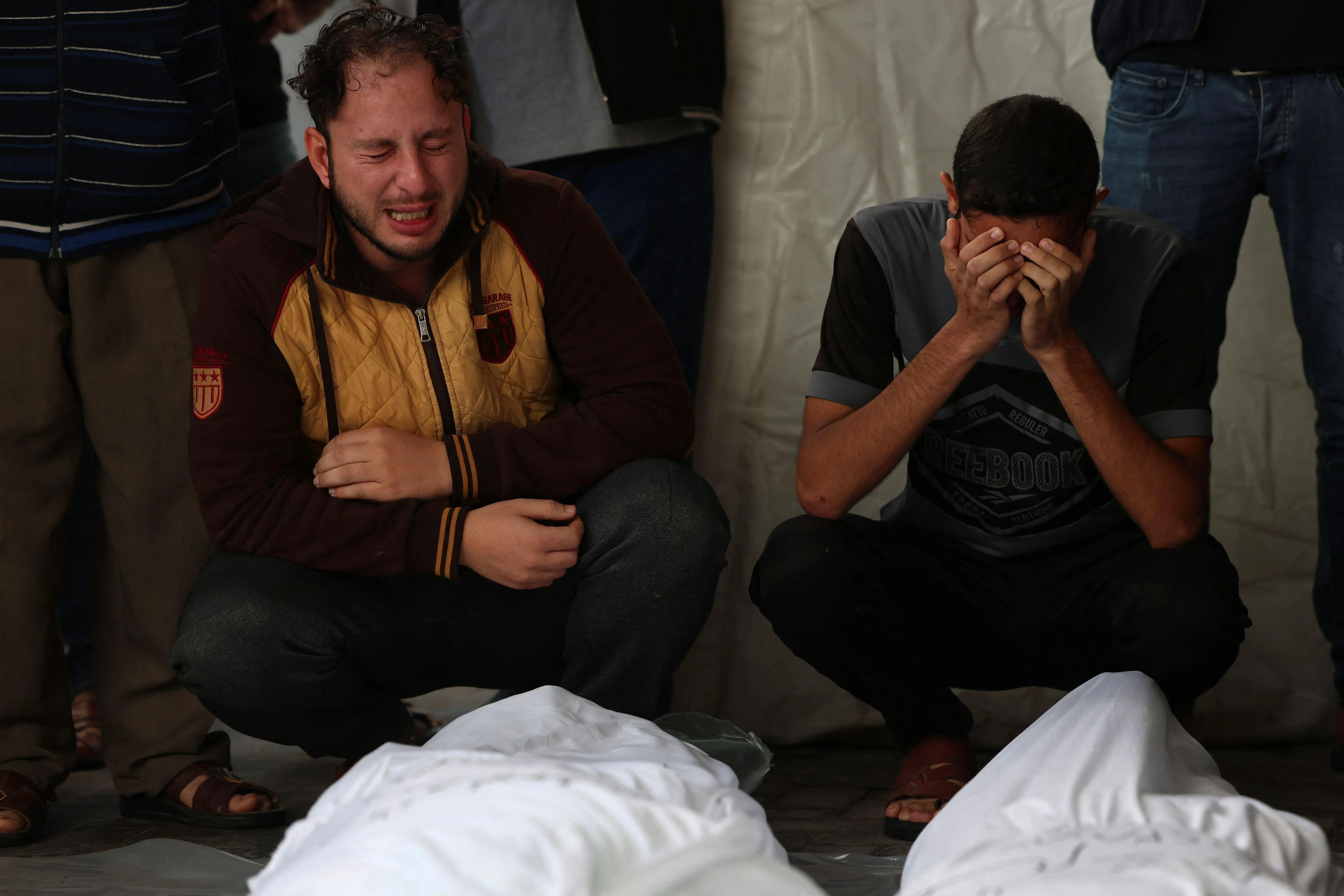 在以哈冲突持续升级的当下，位于加沙南部的拉法频频遭到以军空袭，导致大量巴勒斯坦平民死亡。图为失去亲属的人们在医院停尸房里悲痛哭泣。（法新社）