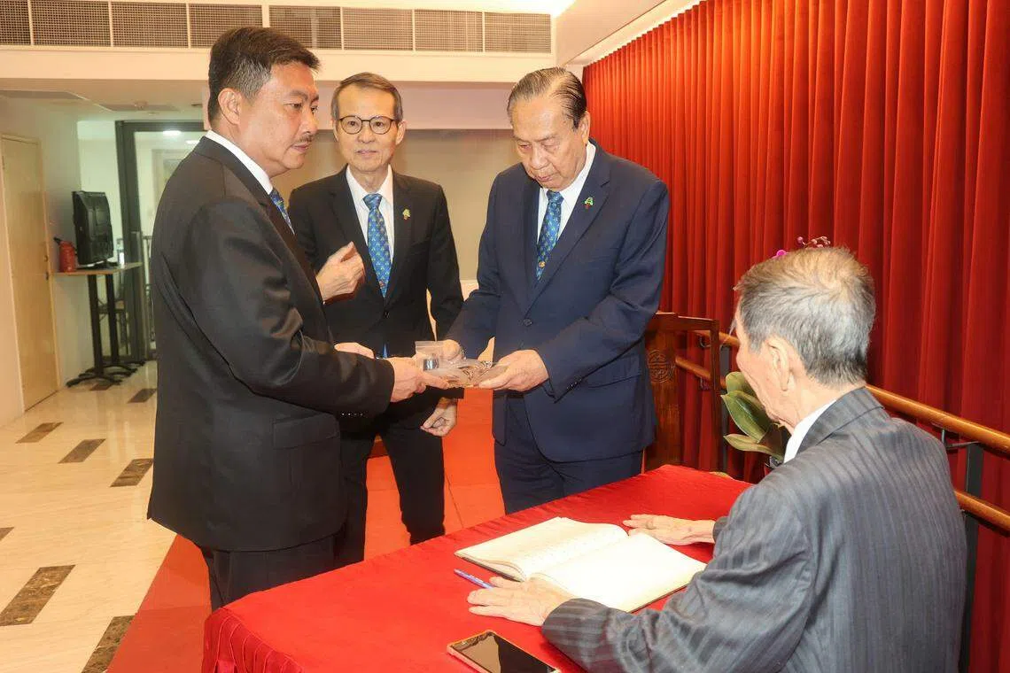 在潮安会馆荣誉主席郑添谅（背对镜头者）的见证下，卸任主席黄锡海（右）交棒给新任主席张学彬（左）。（邬福梁摄）