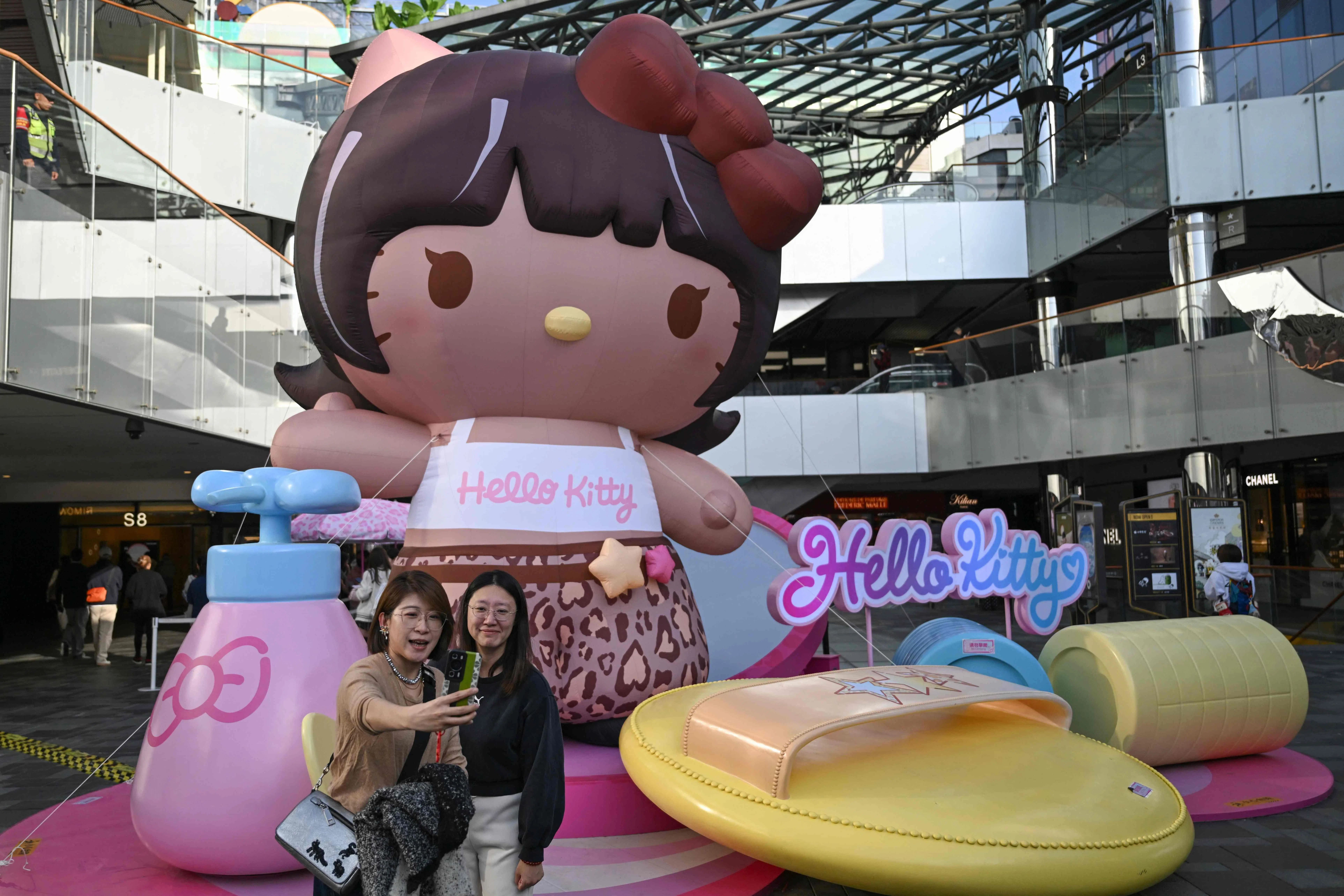 两名Hello Kitty（凯蒂猫）的粉丝10月29日在北京一家购物中心内的巨型Hello Kitty充气娃娃前拍照。Hello Kitty是日本企业三丽鸥旗下的全球知名卡通角色。（法新社）