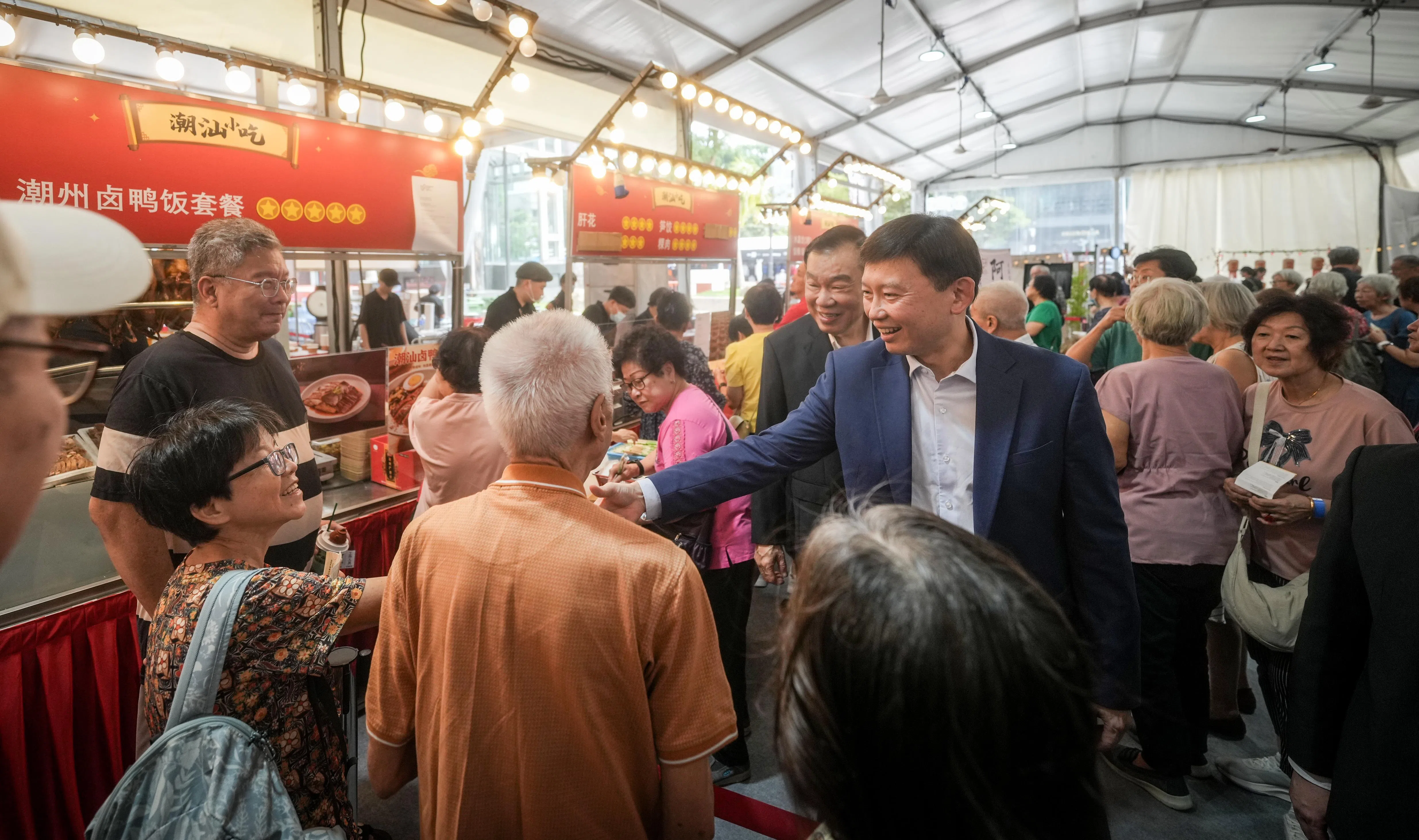 为期三天的义安潮州文化美食节于星期五开幕，在义安广场举行，预计将发送超过1万2000张入场票。图为活动主宾国家发展部长徐芳达走访现场摊位与公众互动的场景。（谢智扬摄）
