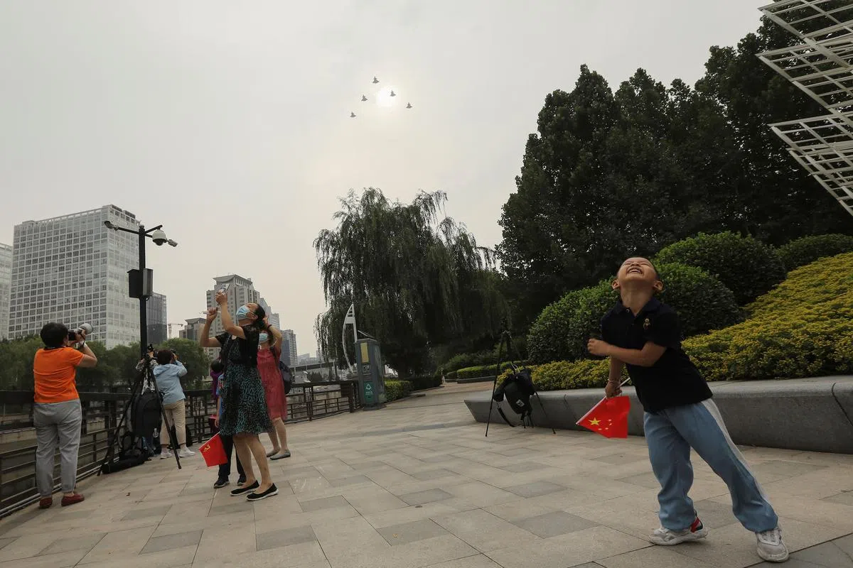 解放军军机为中共党庆大会飞过北京上空，吸引当地民众驻足观看，并用手机和相机捕捉这一刻。（路透社）