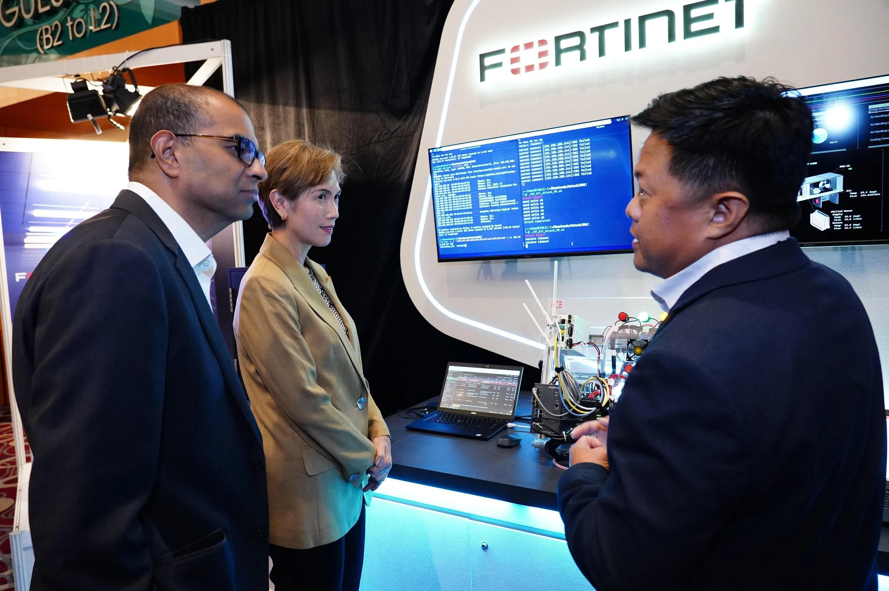 数码发展及新闻部长兼内政部第二部长杨莉明（中）与数码发展及新闻部兼卫生部高级政务部长普杰立医生（左），听取全球网安解决方案供应商飞塔公司代表讲解运营技术的最新发展。（数码发展及新闻部提供）