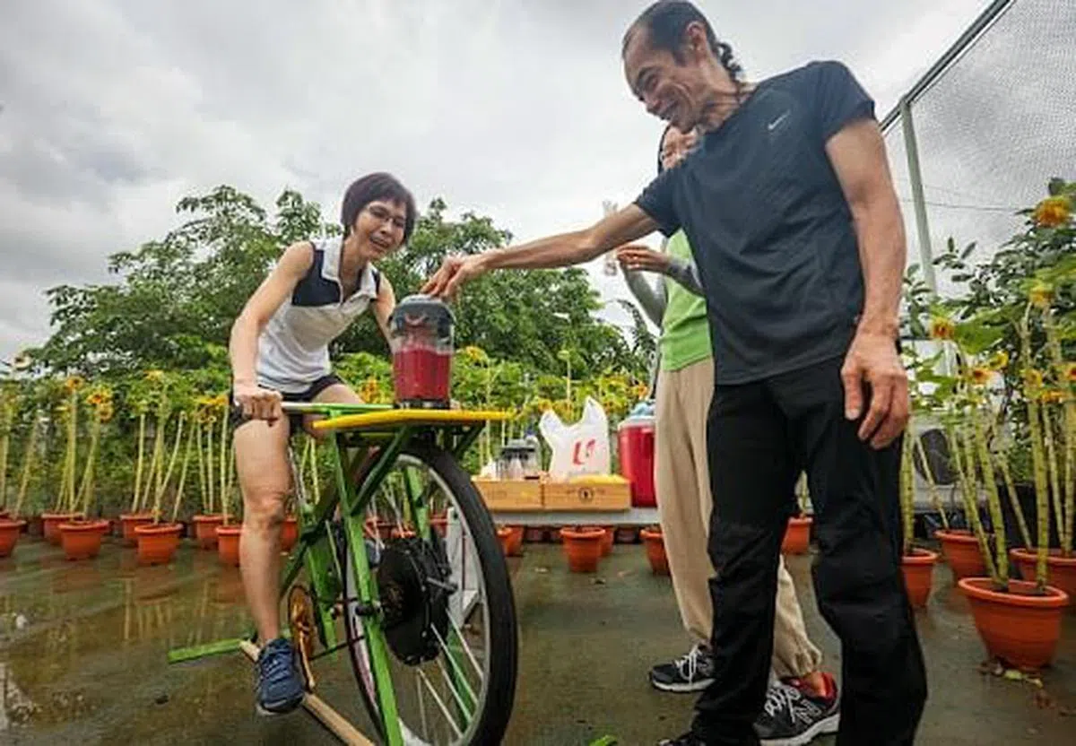 补习教师黄丽霞（左）星期一上午在Sky Sprouts天台农场，尝试使用营养师卢耀源（右）设计的脚踏车，边骑边榨果汁。（叶振忠摄）