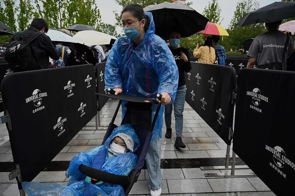 北京环球影城开业首日阴雨绵绵，游客今天冒雨排队等候进入。（法新社）