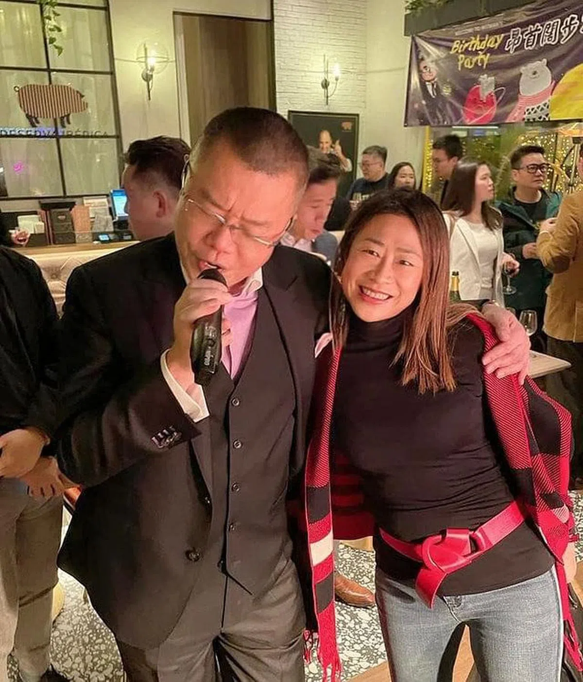 香港流传一张疑是3日宴会上拍摄的照片，图中洪为民左手搭在一名女子肩头，脱下口罩唱歌。该名女子据知为第四界别选委、香港菁英会首位女主席曾凤珠。值得注意的是，照片中的庆生横幅和网传的请帖设计相似。（互联网）