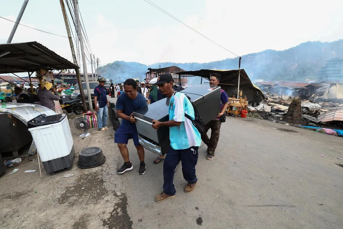 沙巴山打根幸福村的村民在火势受控后，回到家园搬走未被烧毁的家当。（马新社）