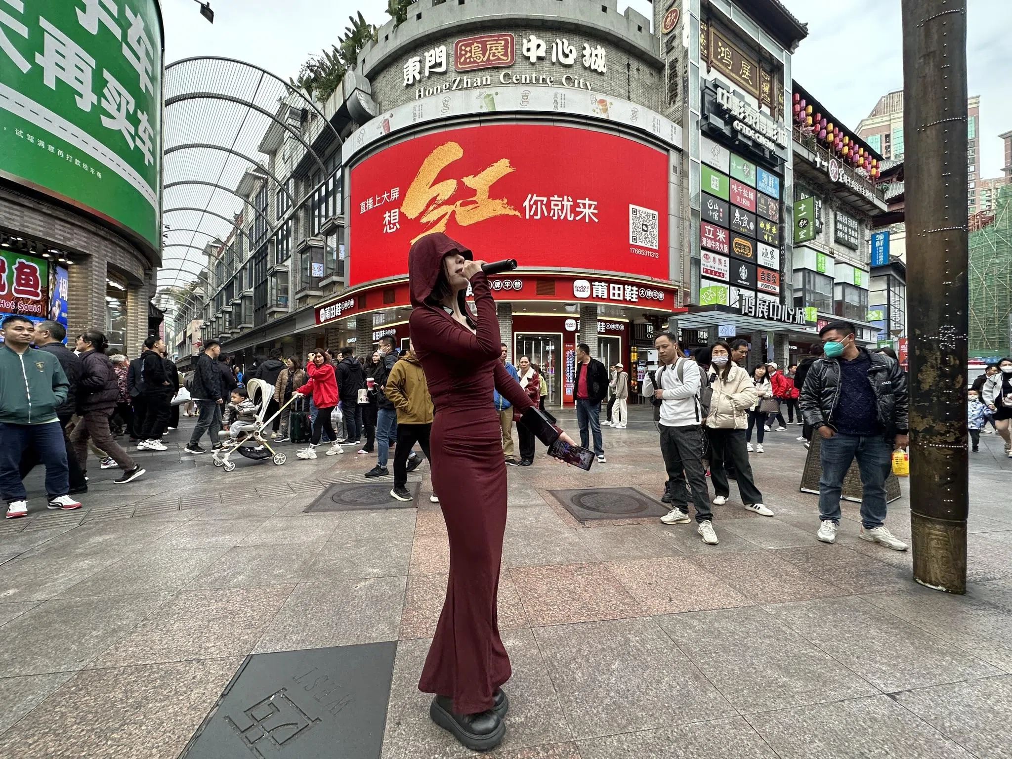 东门大型电子广告牌打出“想红你就来”，公开向更多网红发出邀请。一名网红在东门步行街十字路口直播唱歌。（林煇智摄）