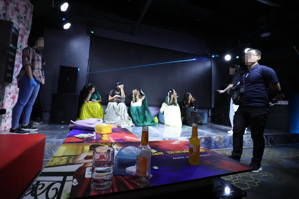 在其中一个被突击的夜总会，五名陪酒女郎并坐在舞台上，看见有媒体的镜头，纷纷捂脸躲避。（梁麒麟摄）