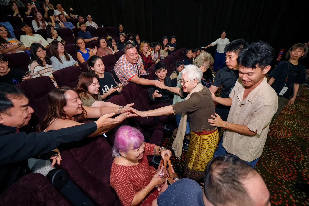 阿嫲Taew（白发弯腰者）和导演Pat（右一）与放映会的观众交流握手。（嘉华院线提供）