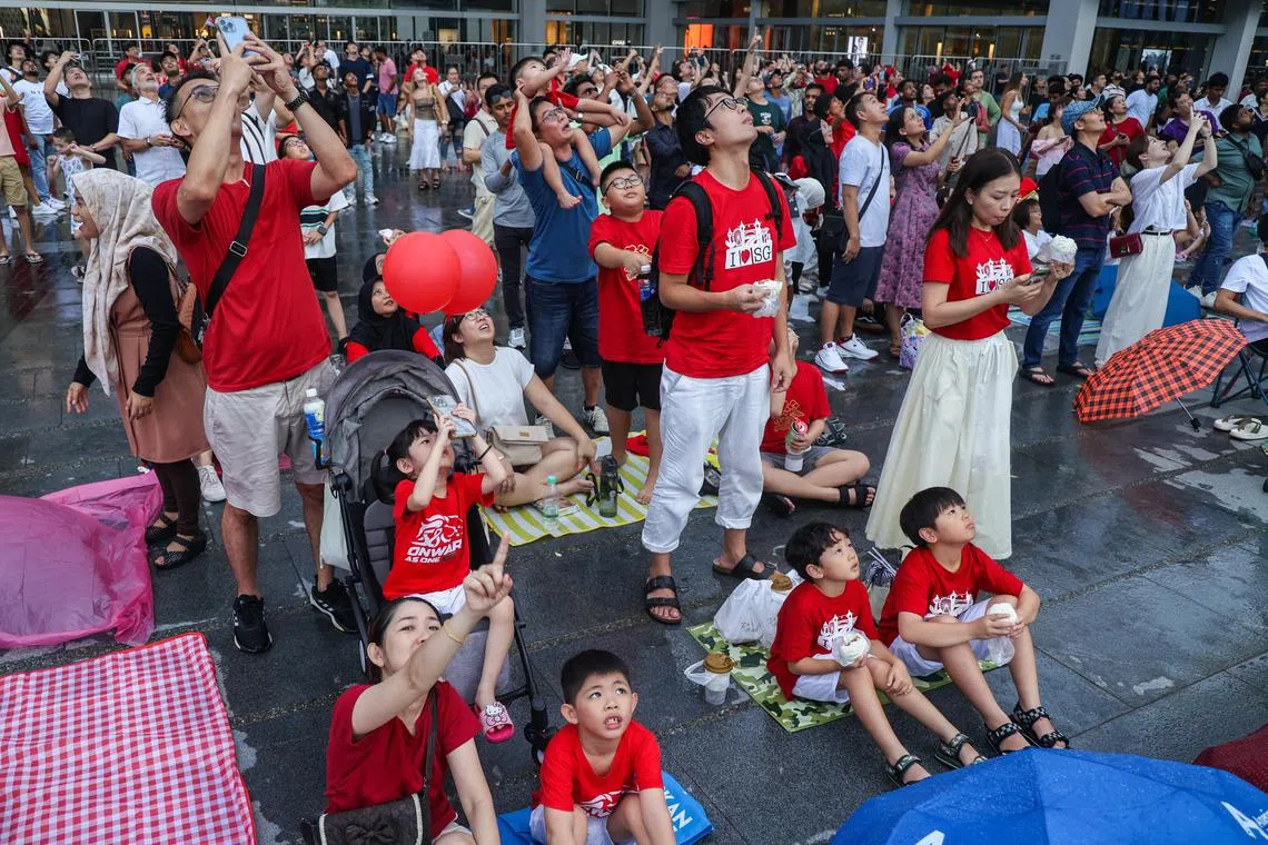 暴雨过后，人们继续留在滨海湾从外围观看国庆庆典的一些环节，当中包括战斗机划破长空呼啸而过的精彩画面。（白艳琳摄）