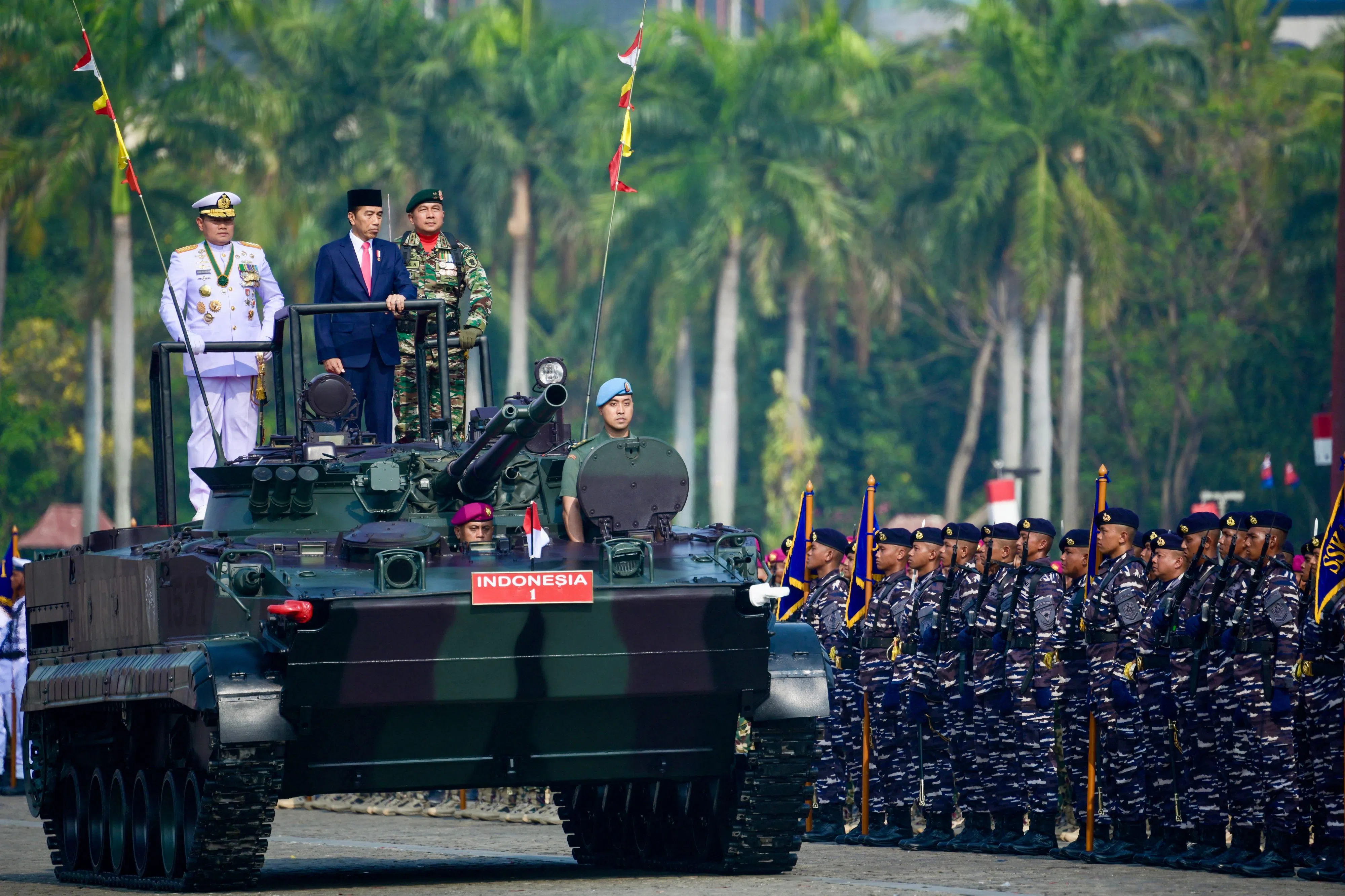 印尼总统佐科（中）和国家武装部队司令尤多（白衣者）一起出席在雅加达举行的武装部队成立78周年纪念活动，在步兵战车上检阅部队。（法新社）