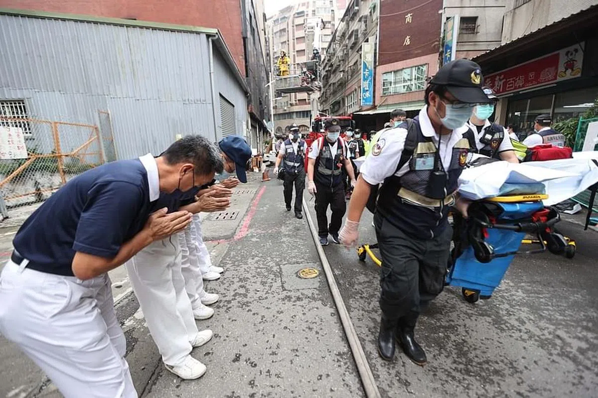 这次火灾死伤惨重，当救援人员抬出罹难住户时，在场义工双手合十拜送。（中通社）