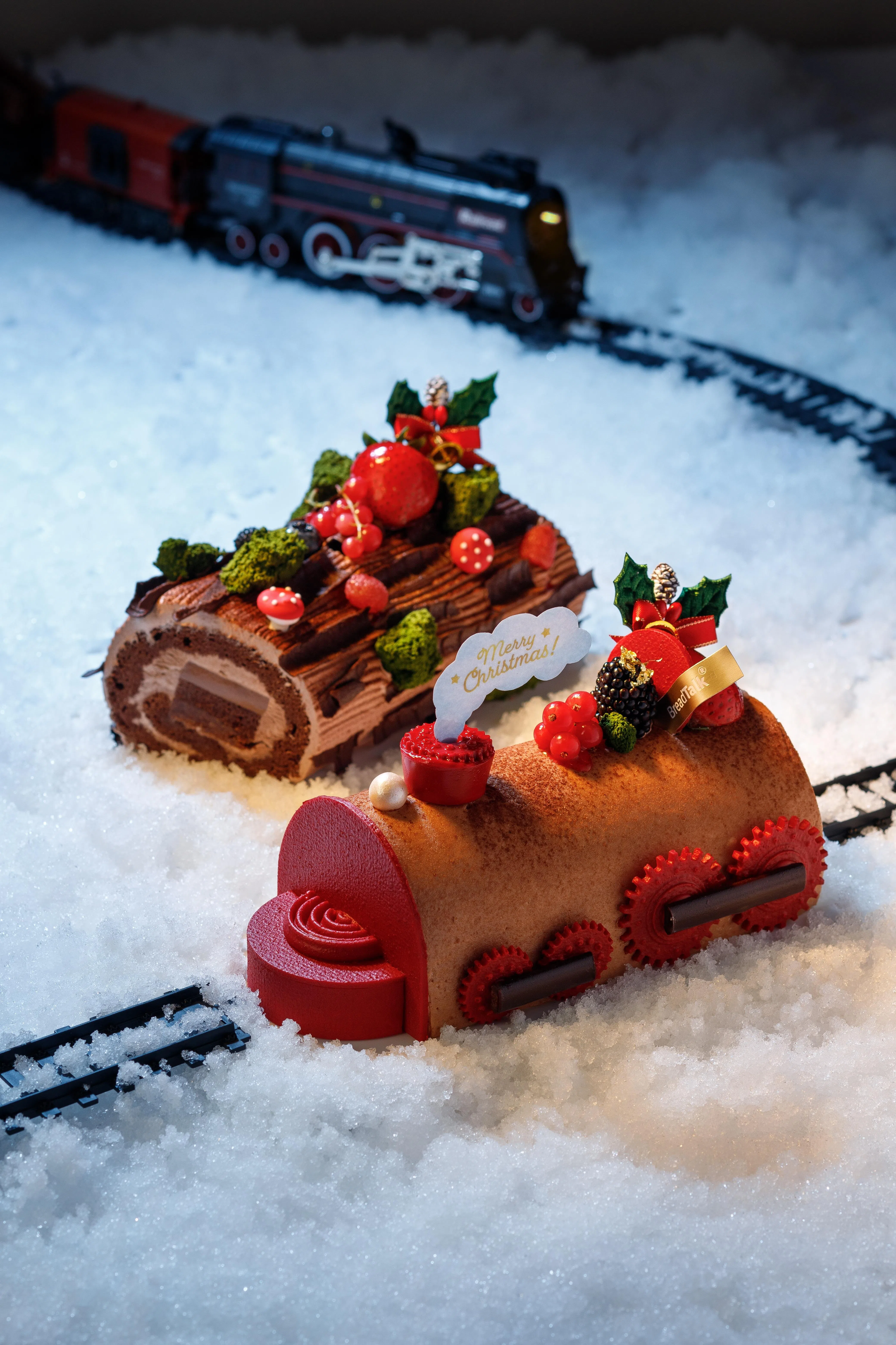 面包物语今年推出的爆米花火车树桐蛋糕（前）和榛果圣诞桐乐蛋糕。（商家提供）