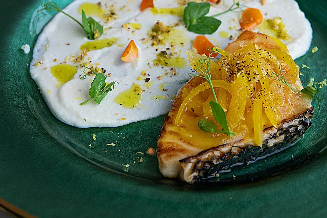 香煎南极银鳕鱼片，搭烟熏椰菜花酱和开心果碎。（餐馆提供）