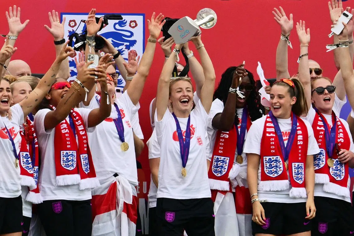 英格兰女队队长莉亚·威廉姆森（中）在球队成功卫冕女足欧锦赛冠军后，回到英格兰在举行的庆祝仪式上捧起奖杯。（法新社）