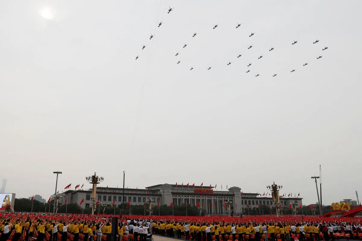 中国军机组成“100”字形，飞过天安门广场上空，参与者也挥举旗帜示意。（路透社）