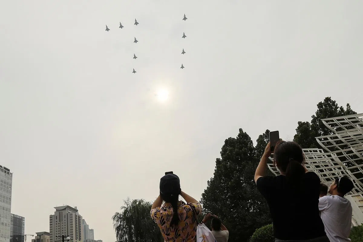 中国军机组成“71”字形，飞过北京上空，当地民众用手机拍下这一刻留念。（路透社）