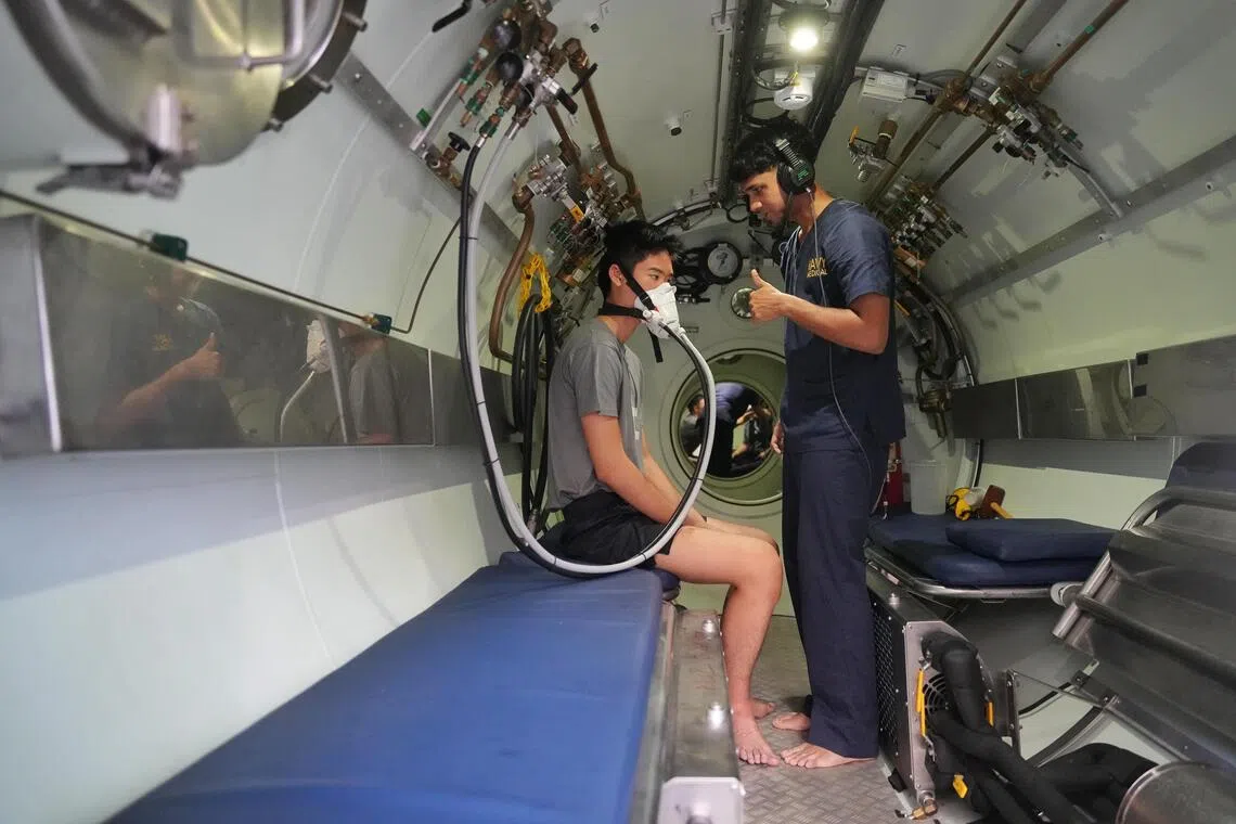 海军水下军医（右）在高压氧舱里为“获救”艇员做模拟治疗，确保他们免受减压伤害。（谢智扬摄）
