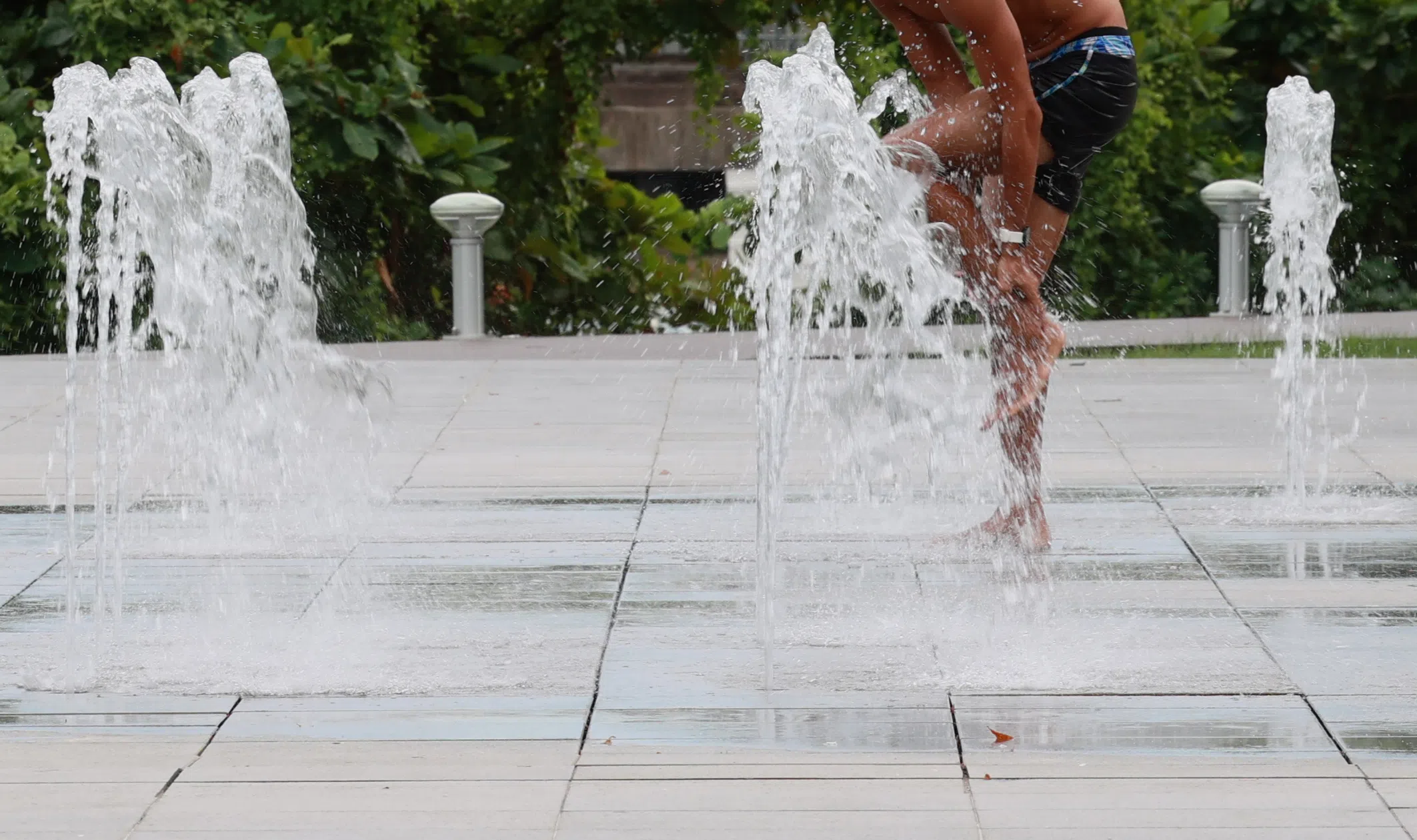 男子来喷泉洗脸与脚。 喷泉附近有一个沙滩排球场地。（潘丰源摄）