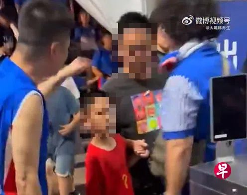 身穿武磊红色国家队球衣的小球迷和父亲被激动的上海申花球迷（蓝衣）围堵，闹事球迷过后被上海警方拘留。 （取自大嘴韩乔生微博）