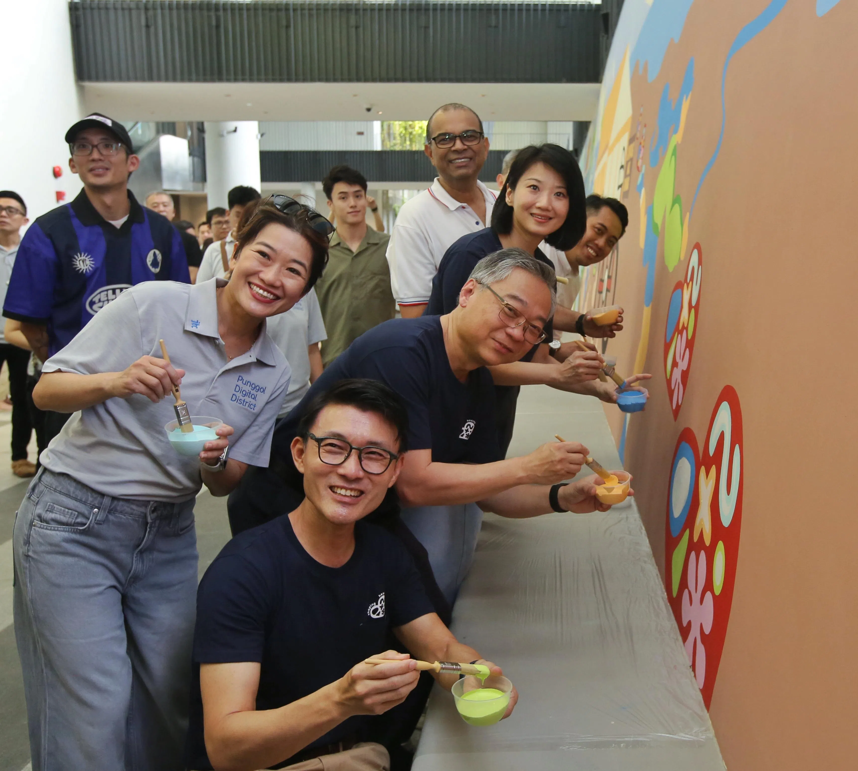 东北区市长马炎庆（中，蹲者）与负责榜鹅集选区的副总理兼贸工部长颜金勇（前右一）、交通部兼国家发展部高级政务部长孙雪玲（后右二）、永续发展与环境部兼教育部高级政务部长普杰立医生（后右三），一起动笔完成《我们的榜鹅故事》壁画。（特约陈福洲摄）