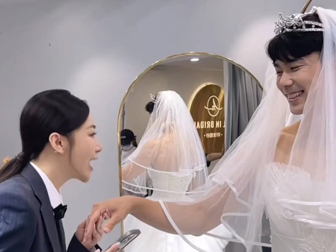 戴向宇（右）为妻子穿上婚纱，两人有说有笑，十分甜蜜。（取自陈紫函微博）