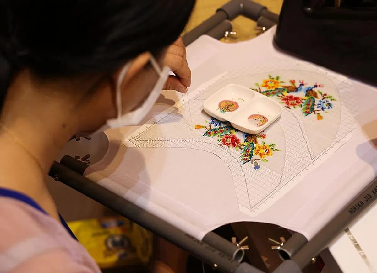 黄俊荣巧妙地用十字绣软件设计打印出珠绣面图案；方便现代绣娘使用的绣框是他使用塑料管再造的。（蔡家增摄）