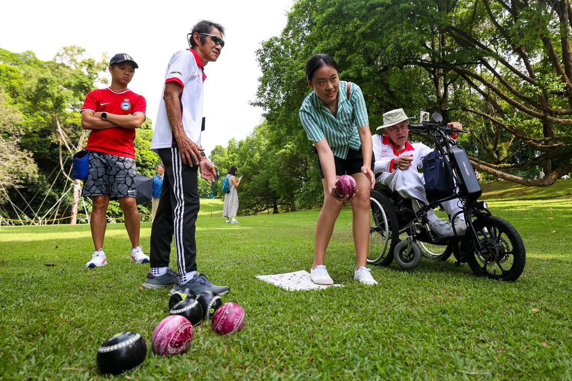 新加坡残疾人草地滚球总会管委会成员许秉雄（右一），在4月19日总统府开放日上，鼓励并指导公众参加草地滚球运动。（林明顺摄）