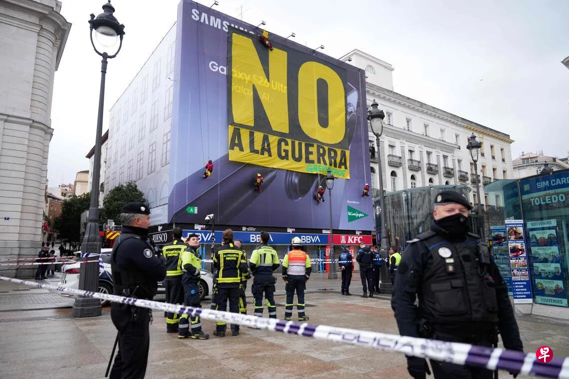 Image 17: 绿色和平组织成员3月10日在西班牙首都马德里的太阳门广场挂起巨大条幅，上面写着“反对战争”，抗议美国和以色列对伊朗的军事打击。警方在示威现场拉起警戒线。 （法新社）
