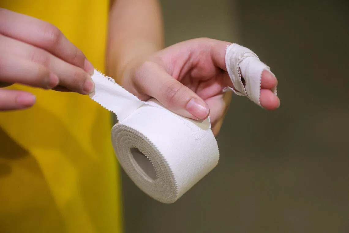 球员在训练前为手指贴上胶带，预防受伤。（游甯稀摄）