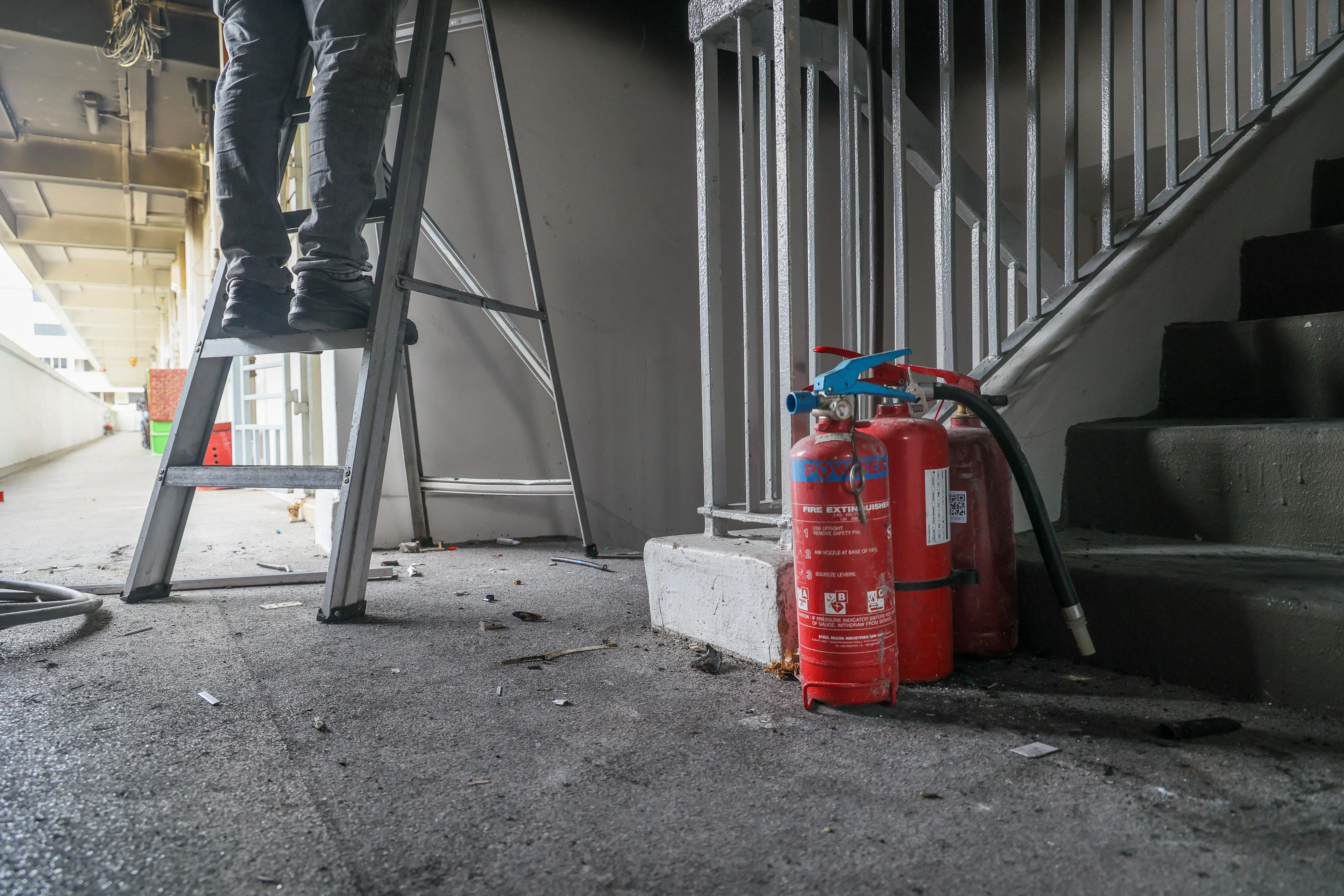 三名男居民事发后提着干粉灭火器上楼灭火，敲门叫居民疏散到安全处。（张俊杰摄）