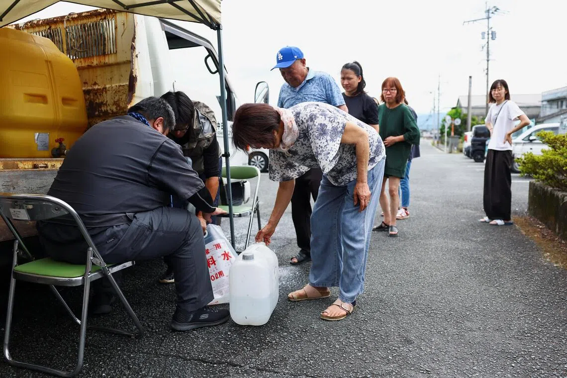 地震灾区八代市断水，当地居民周四在社区中心排队装水。（路透社）
