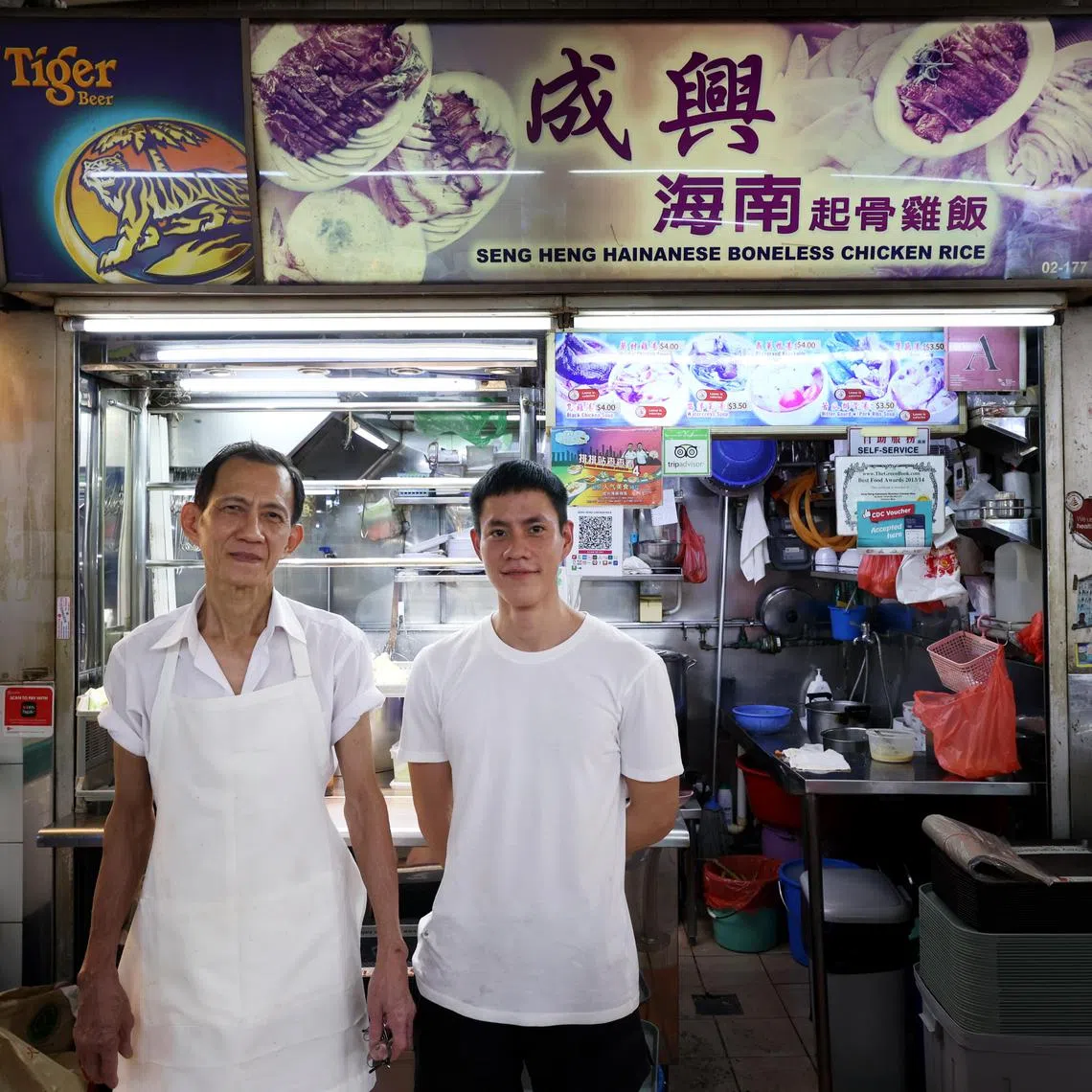 李金贤（左）和儿子李嘉铭（右）一起经营鸡饭生意。（龙国雄摄）