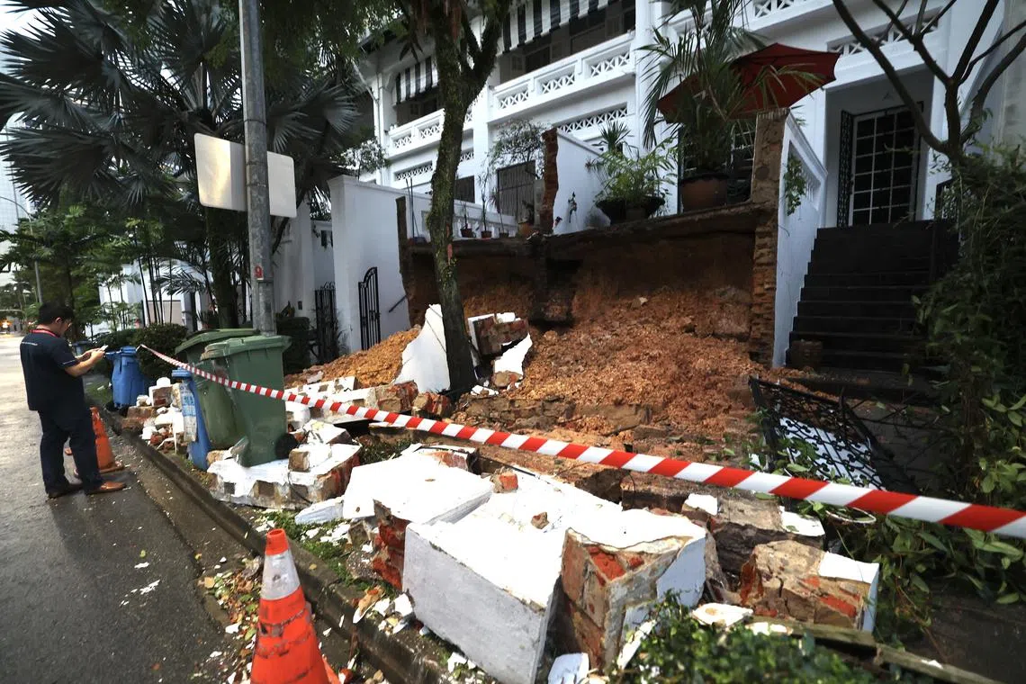 经禧路两栋排屋的挡土墙倒塌后泥土暴露在外，砖头和铁门等结构散落在人行道上。（邬福梁摄）