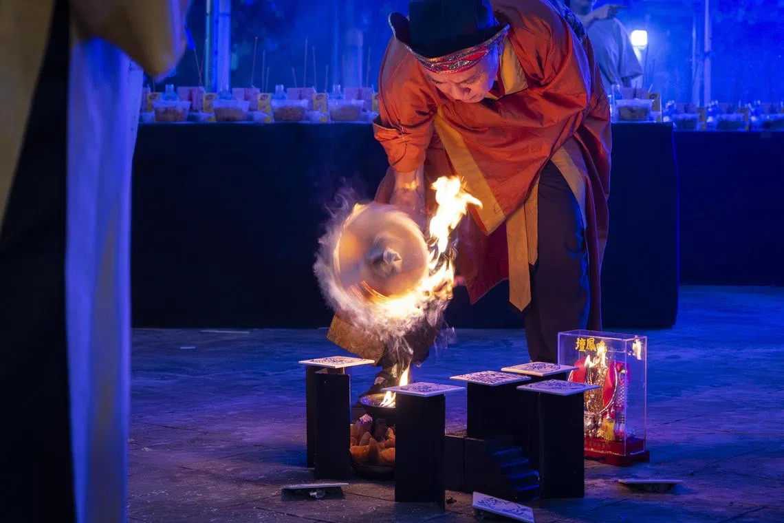 黎师傅用火点燃插在剑上的溪钱（也称买路钱），为开路之用。（龙国雄摄）