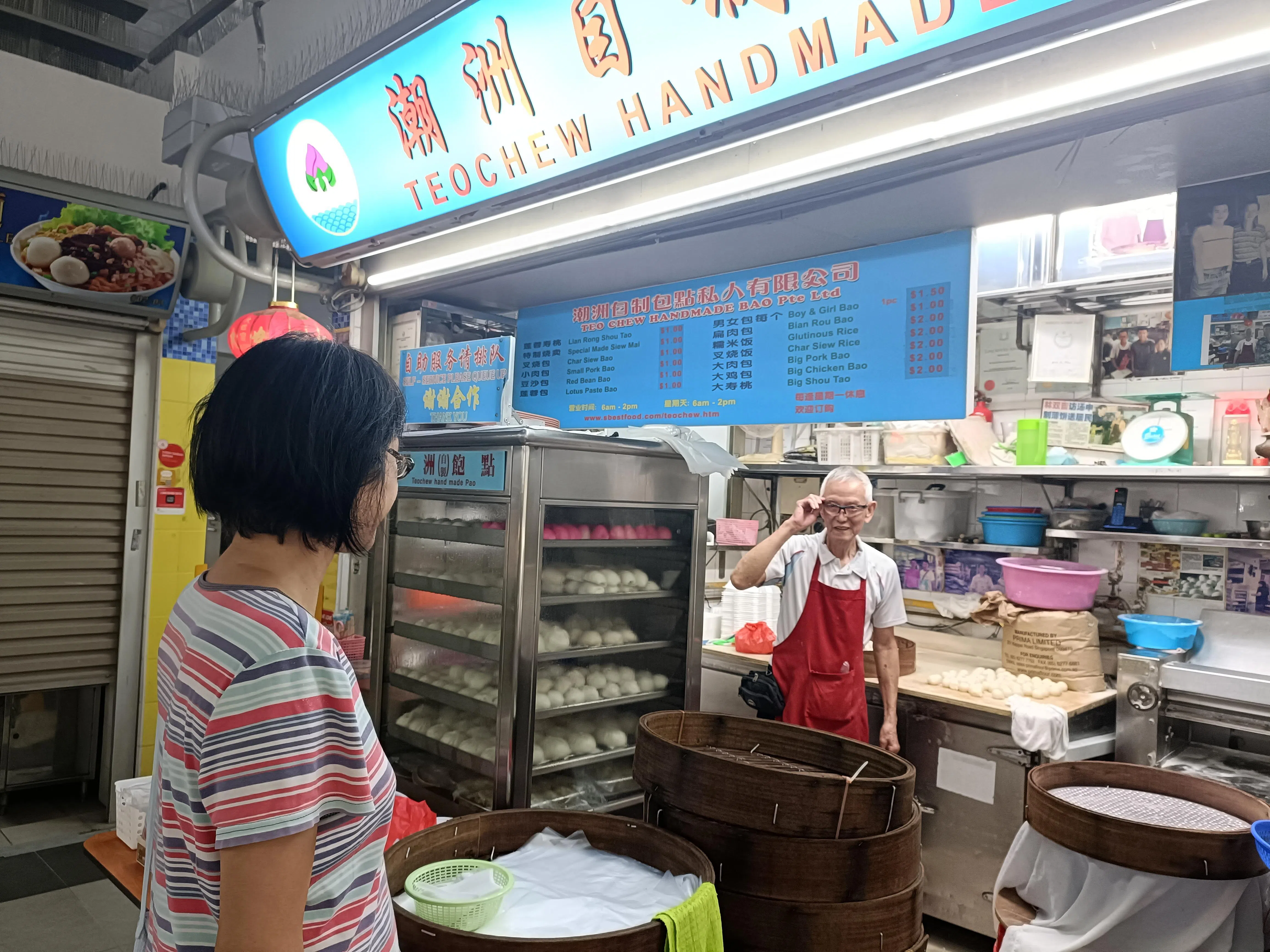 眼看从小吃到大的手工包老店即将歇业，大巴窑居民林素珊（左）震惊落泪，星期三（12月17日）特来与摊主姚誉筹依依道别。（温伟中摄）