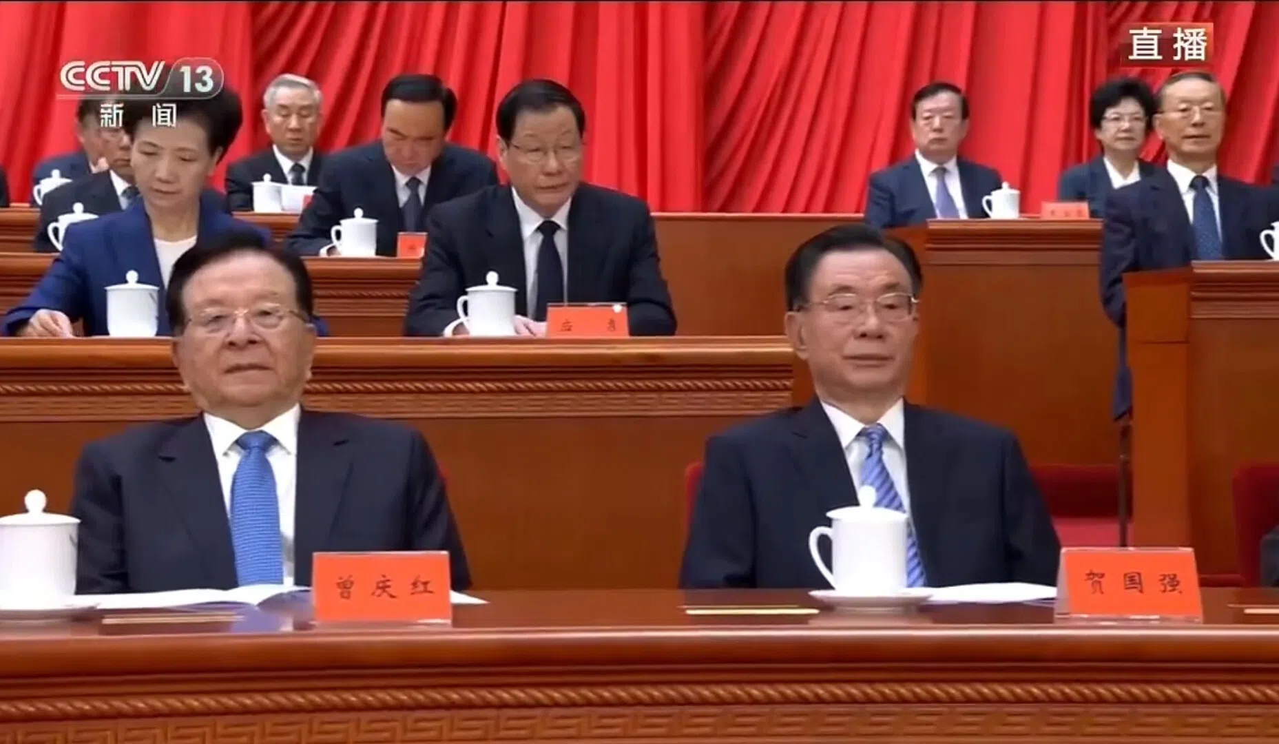 星期一上午，多名中共退休领导人在北京人民大会堂出席纪念江泽民诞辰100周年大会，据央视新闻画面，出席大会的中共元老包括中国前国家副主席曾庆红（前排左）、中共中央前纪委书记贺国强（前排右）。（央视直播视频截图）