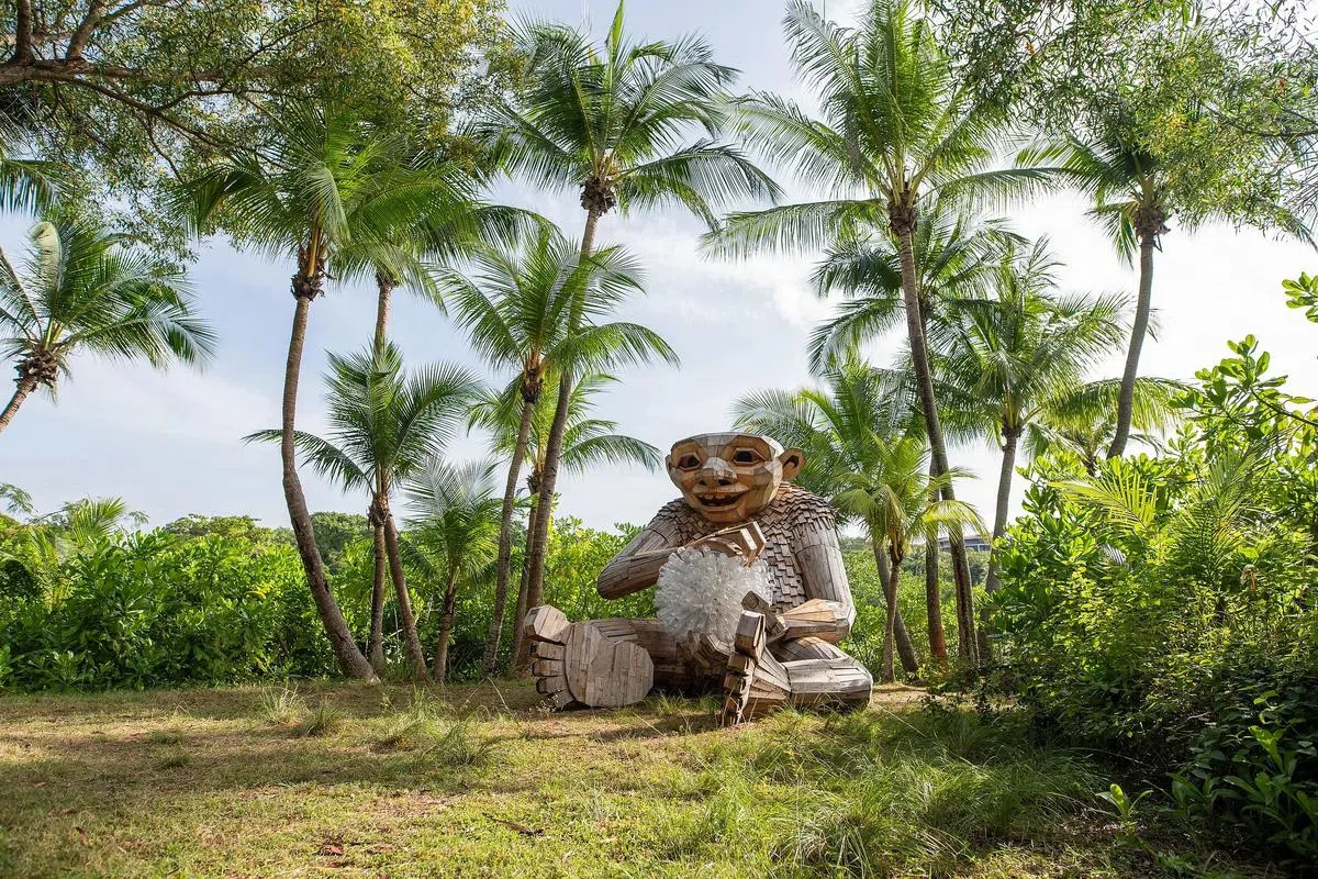 椰树下的巨雕《小人儿琳》手持白色塑料球。（圣淘沙发展局提供图片）