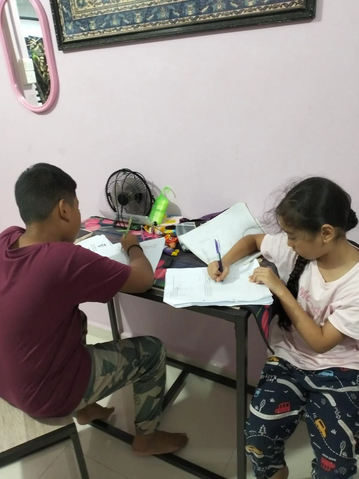奥马尔的11岁儿子和九岁女儿在义顺三房式组屋内做作业。（人民协会提供）
